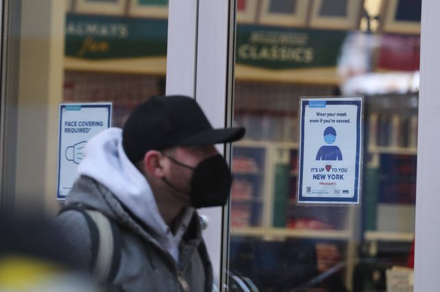 A pedestrian walks past a store with a notice of wearing mask on its door in New York City.